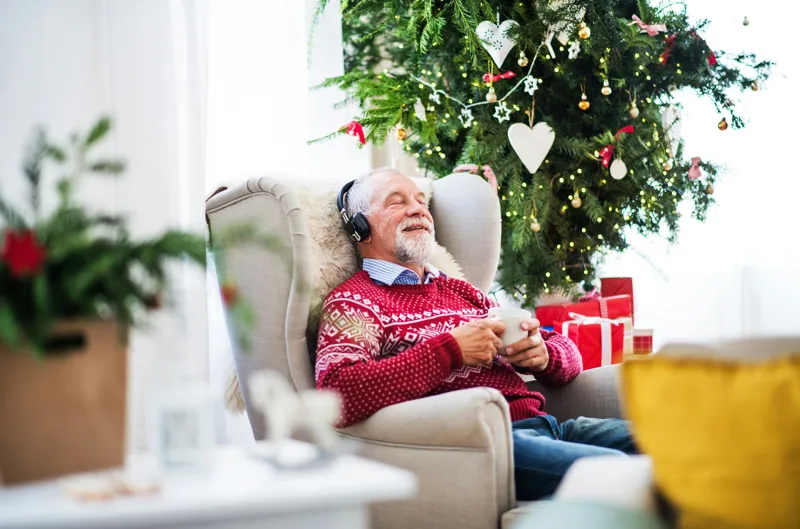 una persona anziana ascolta la musica con un maglione di Natale