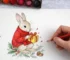 Una mano che colora una immagine che rappresenta un coniglio con un pacco regalo e decorazioni natalizie