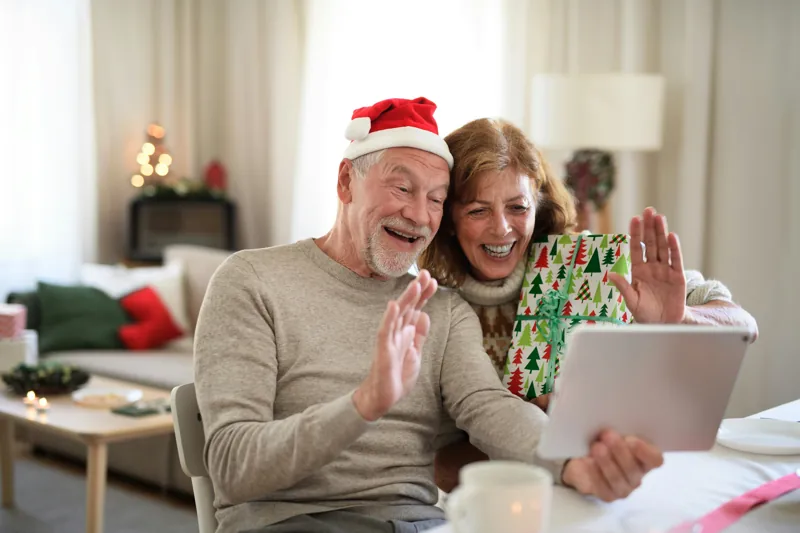 Una coppia di persone anziane fa gli auguri di Natale con una videochiamata sul tablet